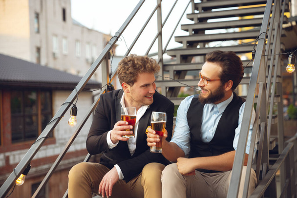 Two men talking, celebrating, look happy, have corporate party at office or bar - 写真・画像