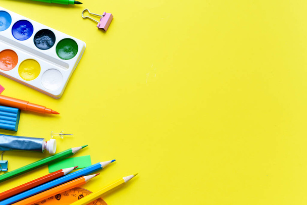 Školní potřeby na žlutém pozadí s místem pro text. Nůžky, barvy, tužky, dětské papírnictví. - Fotografie, Obrázek