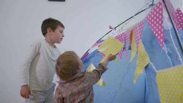 vacances à la maison, les petits enfants masculins s'amusent à décorer avec des drapeaux colorés et des guirlandes de wigwam
 - Séquence, vidéo