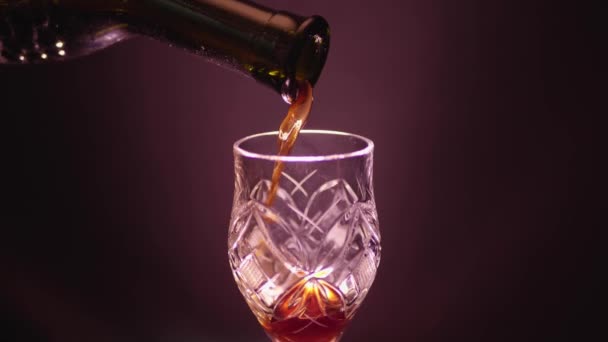 Glass of red wine on a black background with a color cast - Video