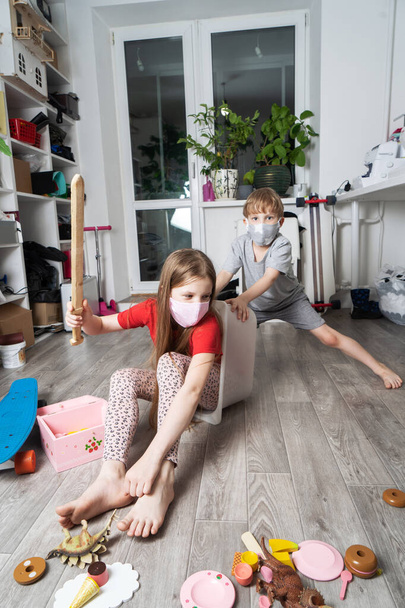 Stay home: Children in medical masks play with toys and ride in a white box. Family lifestyle portrait. - Foto, afbeelding
