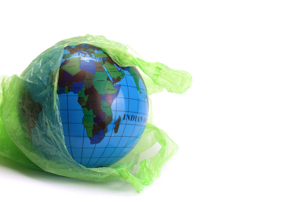 Globe σε μια πλαστική σακούλα σκουπιδιών απομονώνεται σε λευκό. Έννοια μιας περιβαλλοντικής καταστροφής στον πλανήτη - Φωτογραφία, εικόνα