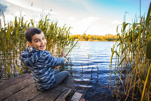 Cute boy catches fish on a summer lake. - Fotó, kép