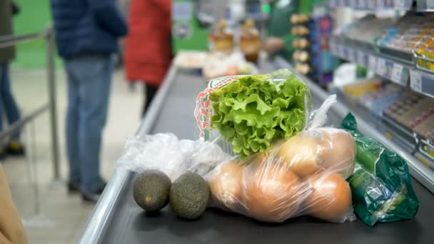 Девушка на кассе в супермаркете распространяет продукты питания в резиновых перчатках на ленте заголовка. Защита от коронавирусов
. - Кадры, видео