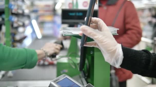 Una donna alla cassa in un supermercato dà a un cliente una carta con un laser dal suo smartphone. Pagare al supermercato in guanti protettivi per non avere coronavirus
 - Filmati, video