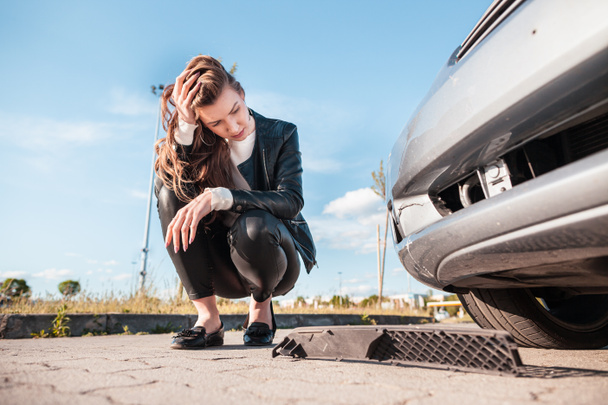 Расстроенный водитель после ДТП. Молодая расстроенная женщина стоит у сломанной машины и ждет ремонта. Концепция придорожной помощи
. - Фото, изображение