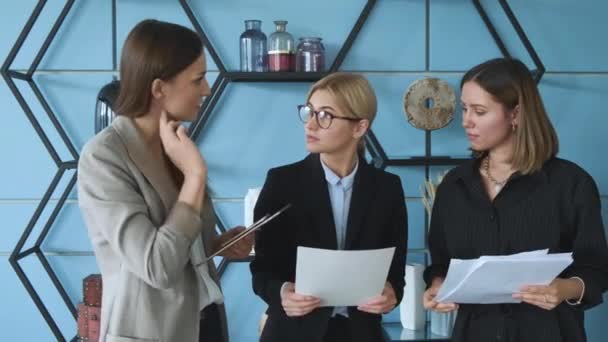 Молодые девушки стоят в офисе и проверяют документы. Три девушки проверяют документы в офисе
 - Кадры, видео