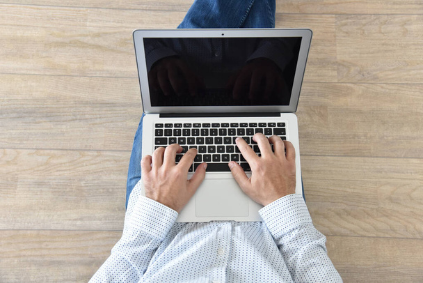 Een man houdt een laptop op schoot. Concept voor achtergrond, website banner, poster, presentatiesjablonen, social media, reclame en drukwerk.  - Foto, afbeelding
