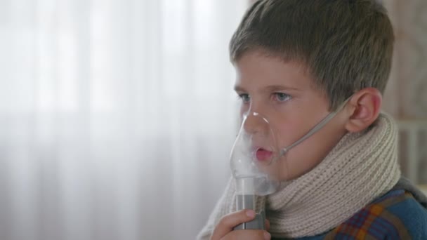 pandemie, een klein schattig mannelijk kind voelt zich niet goed, begint met hoesten of ademhalen, gebruikt een vernevelaar - Video