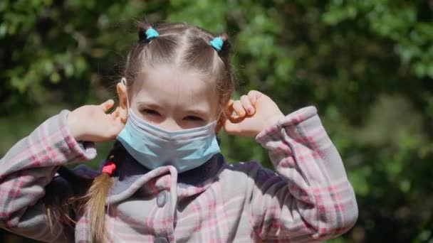 Little girl takes off medical mask and breathes deeply and smiling looking at camera - Materiał filmowy, wideo