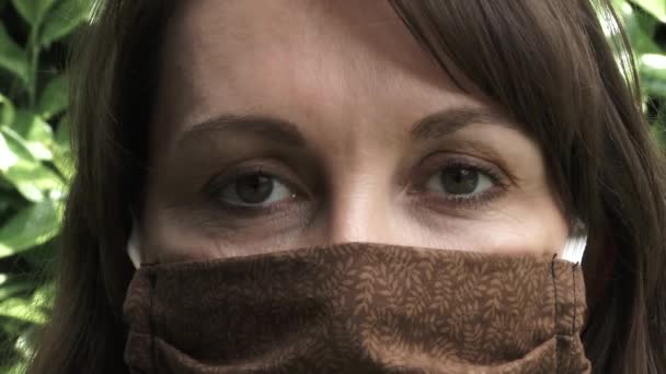 COVID-19中に自家製フェイスマスクを身に着けている女性のクローズアップが、彼女の目のメガネを曇らせることに問題があります. - 映像、動画