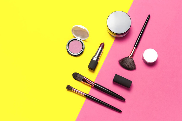 Professional makeup brushes, powder, eyeshadow, blush, lipstick on yellow pink background flat lay top view copy space. Beauty product women's accessory fashion. Different brushes. Cosmetic makeup Set. - Photo, Image