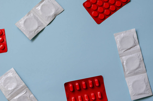 Gesundheitswesen und Medizin Hintergrund. Gruppe zufälliger Pillen, medizinischer Pillen und Kondome auf hellblau. Behandlung und Prävention sexueller Dysfunktion bei Männern. Blick von oben schräg. Kopierraum - Foto, Bild