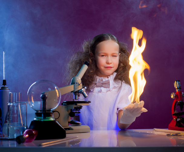 Smiling girl shows chemical trick - fire in palm - Photo, image