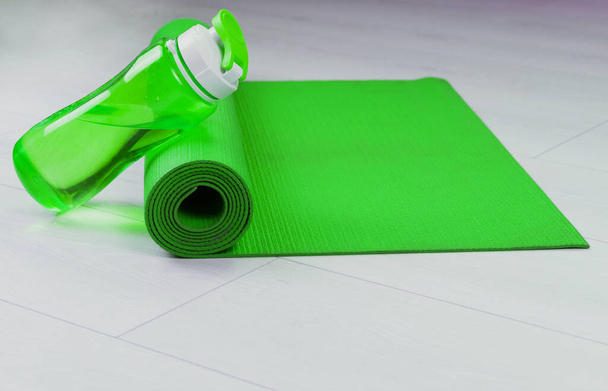 Yoga mat en groene fles water. Kopieerruimte. - Foto, afbeelding