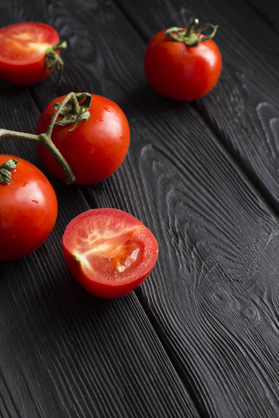 Red cherry  tomatoes on the black wooden background. Location vertical. Copy space. - Photo, Image