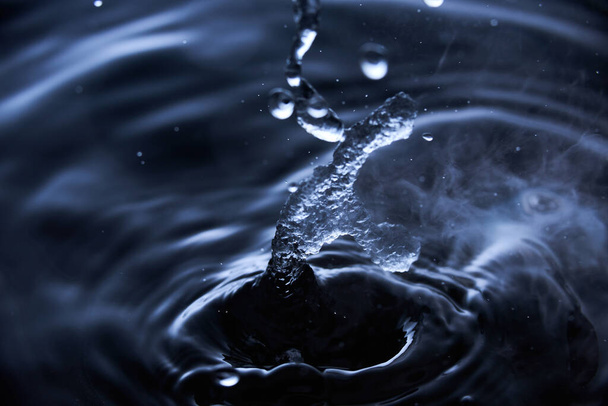 Boiling water splash with steam on dark blue background closeup. - Photo, image