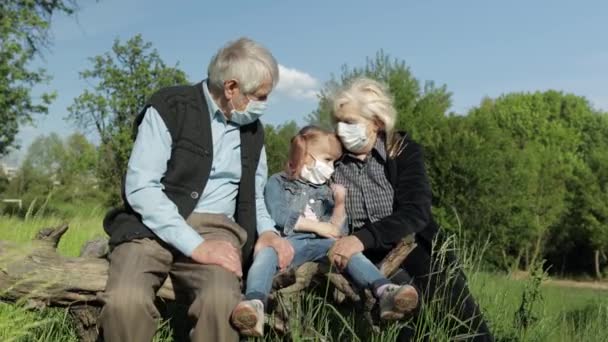 Großeltern mit Enkelin in medizinischen Masken im Park. Coronavirus-Quarantäne - Filmmaterial, Video
