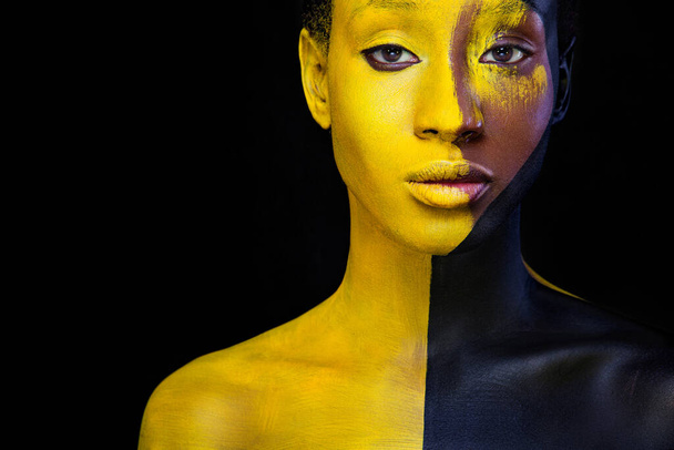Woman with black body paint. Cheerful young african girl with art bodypaint. An amazing model with yellow makeup. Closeup face. - Valokuva, kuva