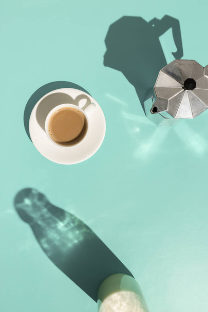 Café con leche y cafetera sobre fondo abstracto de menta pastel vista aérea con espacio para copiar. Concepto de cafetería mínima
 - Foto, imagen
