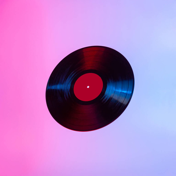 Disque vinyle LP noir éclairé avec une lumière colorée. Espace de copie. Concept minimal créatif
. - Photo, image