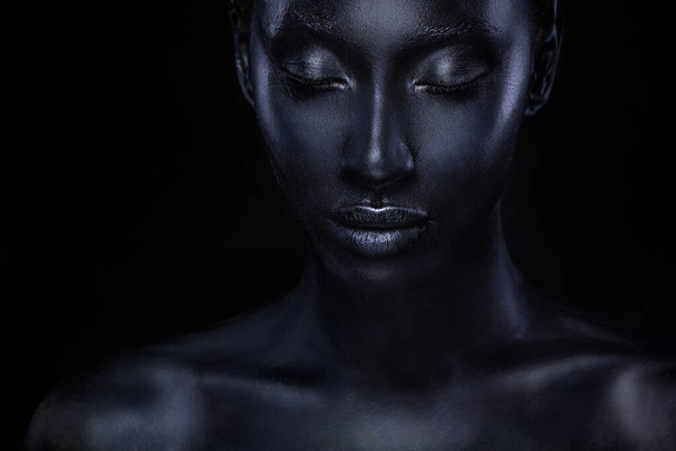 Woman with black body paint. Cheerful young african girl with bodypaint. An amazing model with art makeup. Closeup face. - Фото, зображення