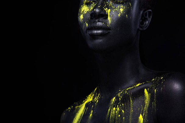 Woman with black body paint. Cheerful young african girl with art bodypaint. An amazing model with yellow makeup. Closeup face. - Fotografie, Obrázek