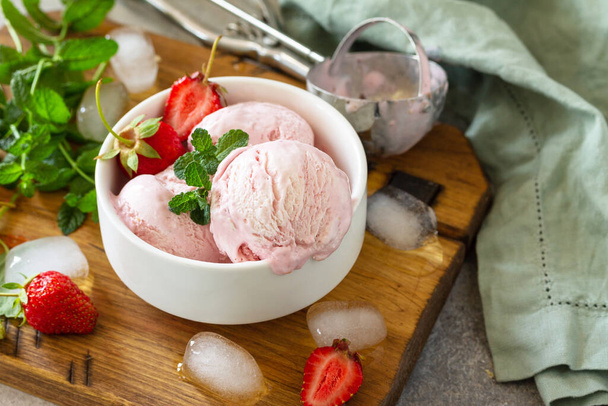 Helado de fresa orgánico casero. Bolas de helado de fresa con hojas de menta en una mesa de piedra clara o pizarra
. - Foto, Imagen