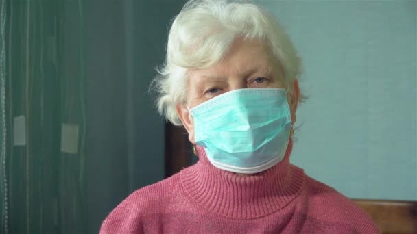 Portrét pozitivní staré ženy s obličejovou maskou během epidemie koronaviru COVID-19 zblízka - Záběry, video