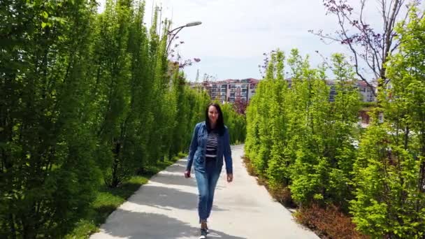 young woman walks along alley in city park. - Záběry, video
