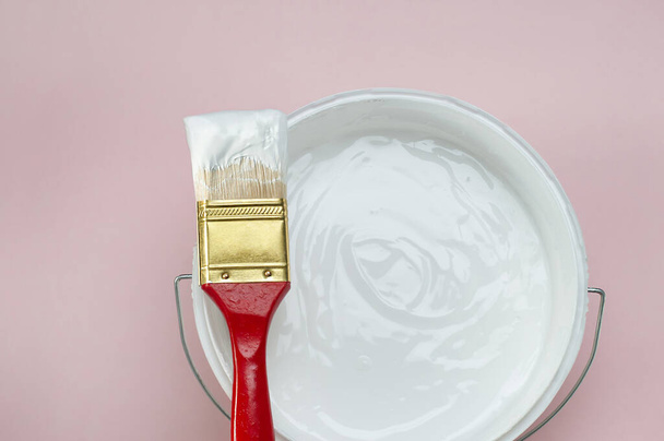Huisreparatie, penseel met een emmer witte verf - Foto, afbeelding