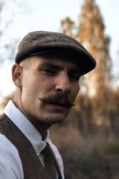 Ретро 1920-х годов портрет английского гангстера с плоской кепкой. Курит сигарету на улице
.. - Фото, изображение