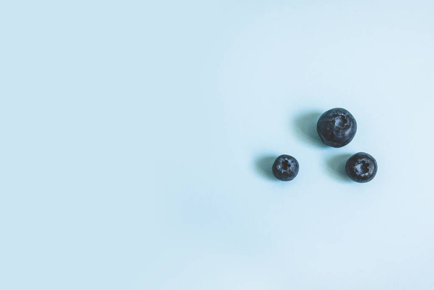 Ripe blueberry berries on blue background, top view, flat lay - Foto, afbeelding