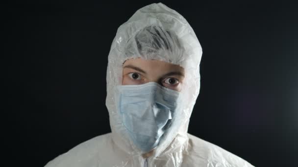 arts in beschermend pak en masker applaudisseert, coronavirus pandemie covid-19 kijkt naar de camera - Video