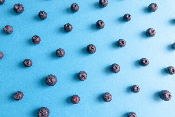Fresh ripe blueberry berries pattern on blue background. - Photo, Image