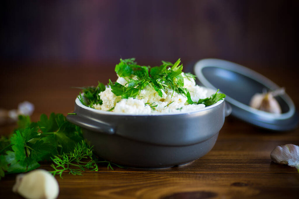 salted homemade cottage cheese with garlic and herbs in a bowl on a wooden table - Foto, Imagen