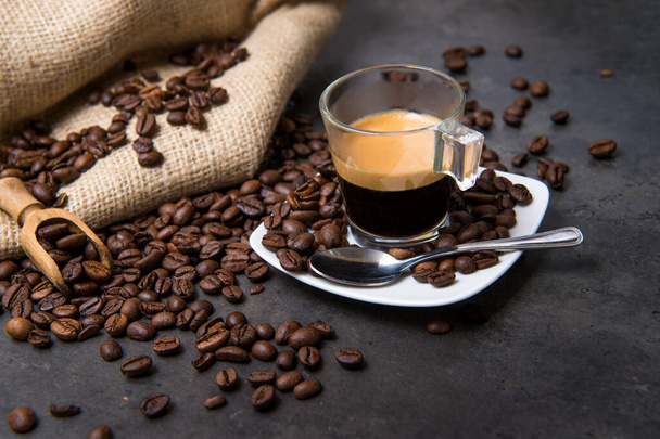 real italian espresso coffee in a glass cup on a black floor with coffee beans cutting light - Photo, Image