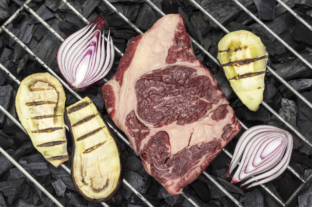Raw marbled beef steak with eggplant and onions on charcoal grill. Organic food. Flat lay - Фото, зображення