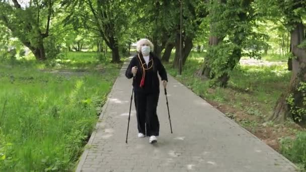 Активная пожилая женщина в маске тренируется Нордическая ходьба в парке на карантине
 - Кадры, видео