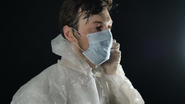 vermoeide arts in een beschermend pak doet een medisch masker af en applaudisseert met handschoenen, vecht tegen coronavirus pandemie covid-19 - Video