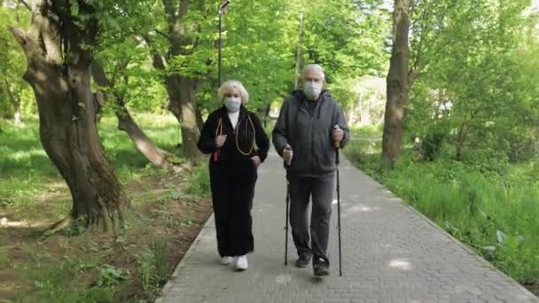 Actieve oudere man, vrouw die Nordic walking traint in het park tijdens quarantaine - Video