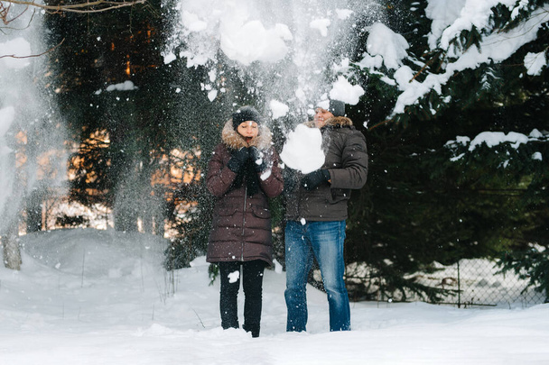 chico y chica al aire libre en un paseo de invierno jugando bolas de nieve y trineo
 - Foto, Imagen