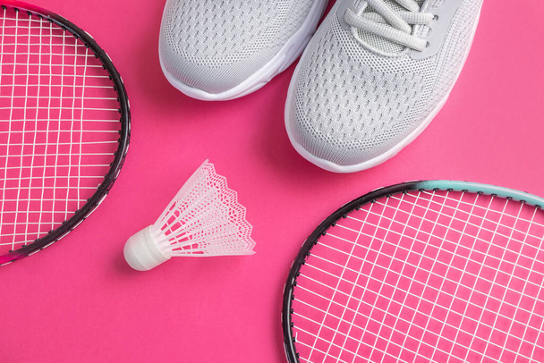 Sapatilhas, raquetes de badminton e vaivém em um fundo rosa brilhante. O conceito de equipamento para esportes amadores. Minimalismo
. - Foto, Imagem
