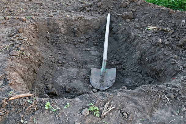 Gödröt ás. Feküdj a földbe. Az ásó a gödörben van.. - Fotó, kép