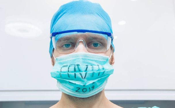 young man surgeon doctor in uniform and goggles in operating room during coronavirus pandemic. - Foto, Bild