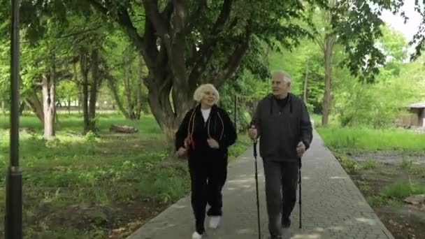 Aktív idős pár. Férfi képzés Nordic walking, nő fut a parkban - Felvétel, videó