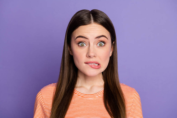 Closeup photo of attractive terrified lady biting lips made big mistake eyes full of fear feel guilty wear casual orange striped t-shirt isolated pastel purple color background - Foto, afbeelding