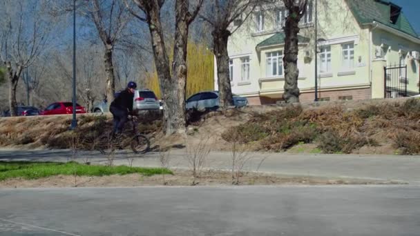 Junger BMX-Fahrer springt mit Drehung über Rohr im Skatepark. - Filmmaterial, Video