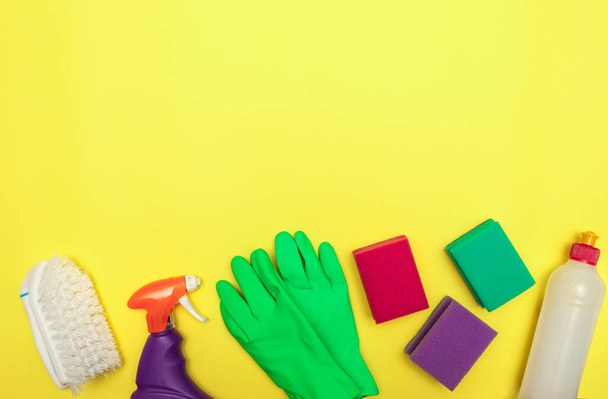 Gloves, cleaning agent and brush on a yellow background, cleaning. Washing dishes. Flat lay. Space for text - Foto, afbeelding