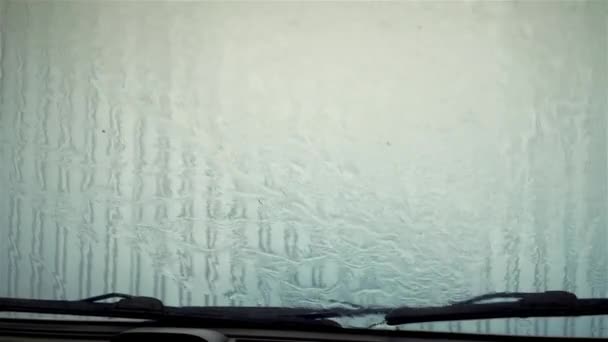 Primo piano dell'acqua sul parabrezza. Pioggia su vetro. Auto in autolavaggio lavaggio veicolo. Gocce saponose scorre giù vetro
 - Filmati, video